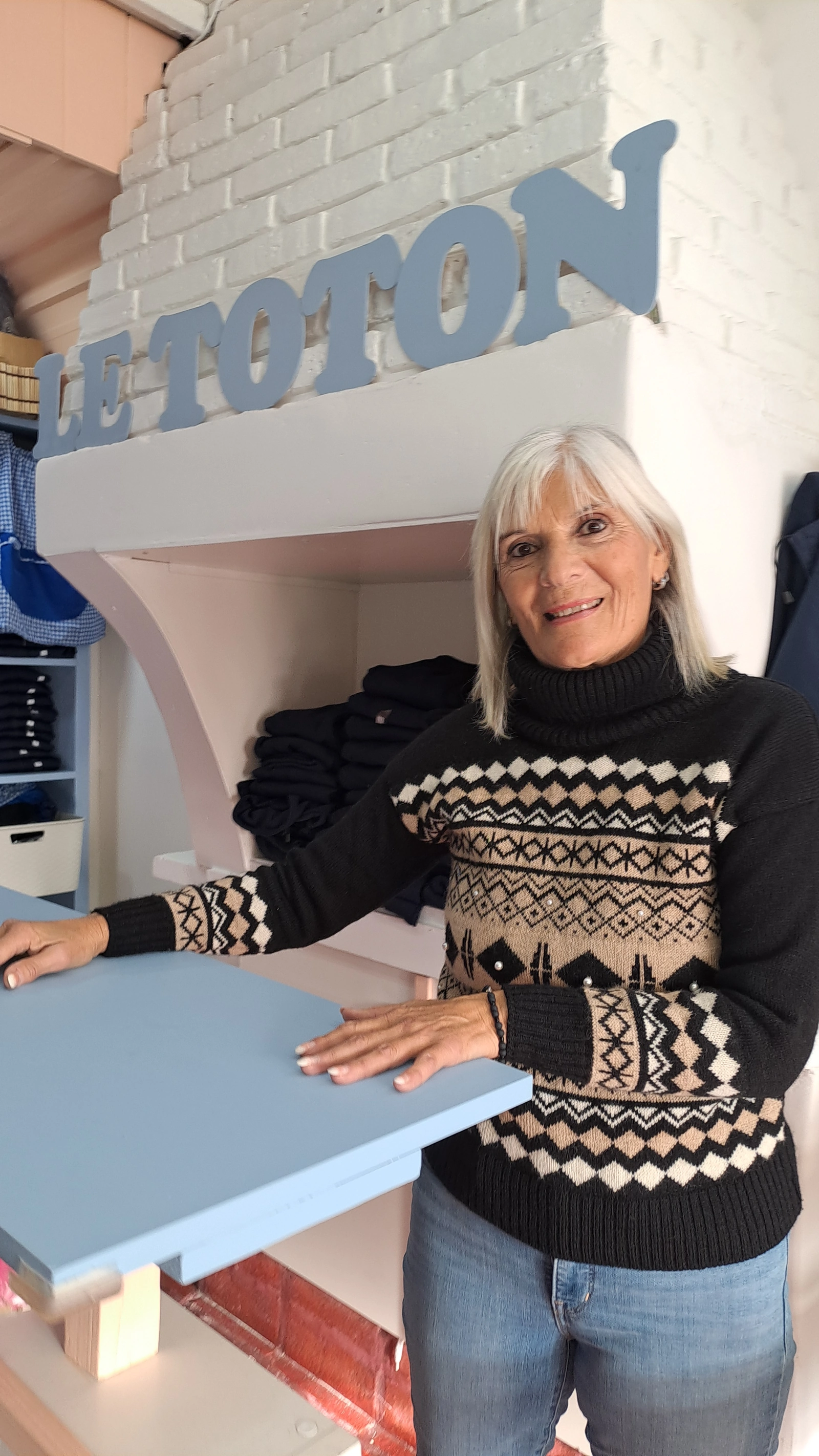 Interior de Le Totón con una persona detrás del mostrador y el nombre del negocio sobre una pared blanca